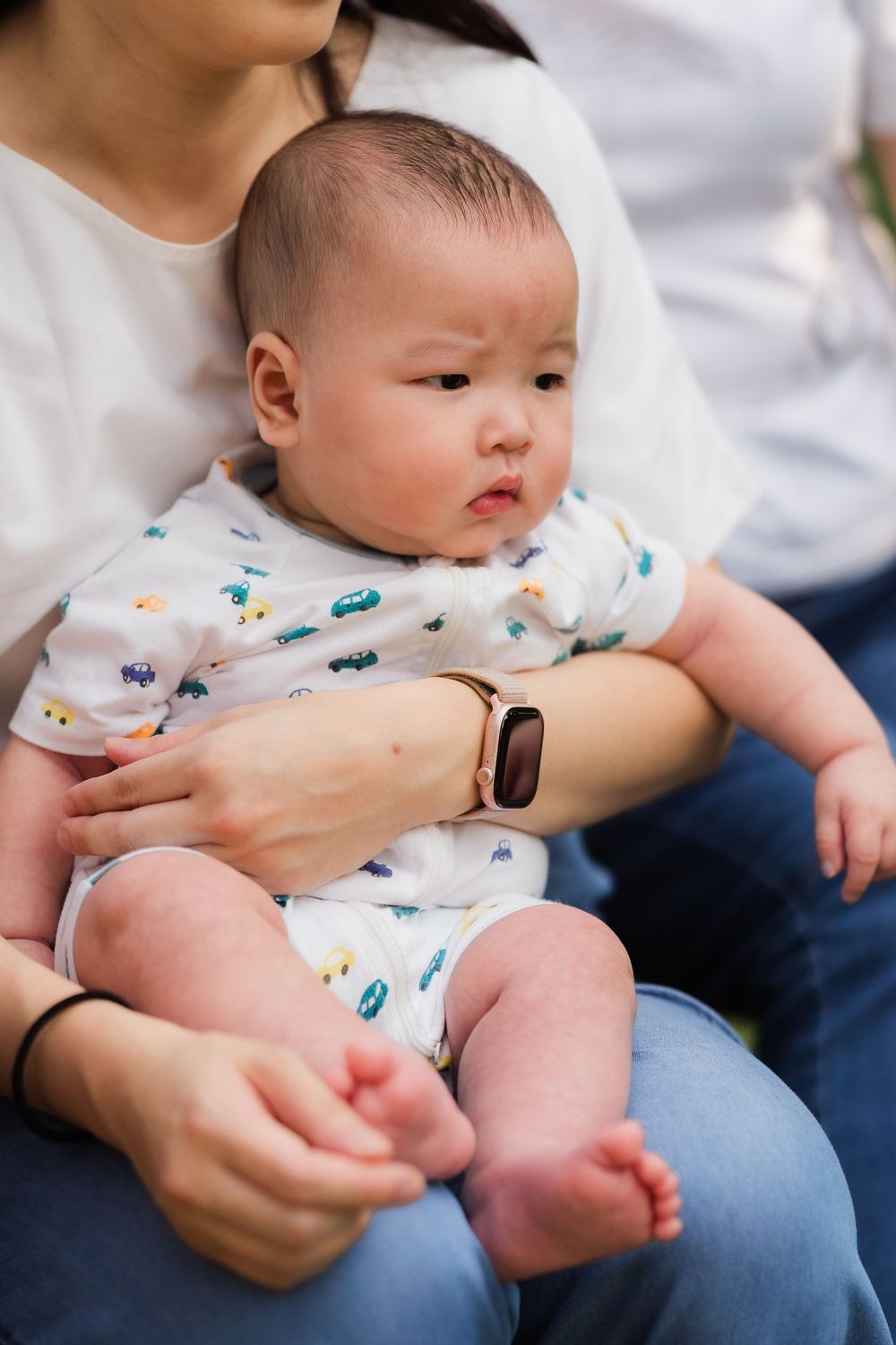 Mother holding newborn baby in white onesie with colorful print.
