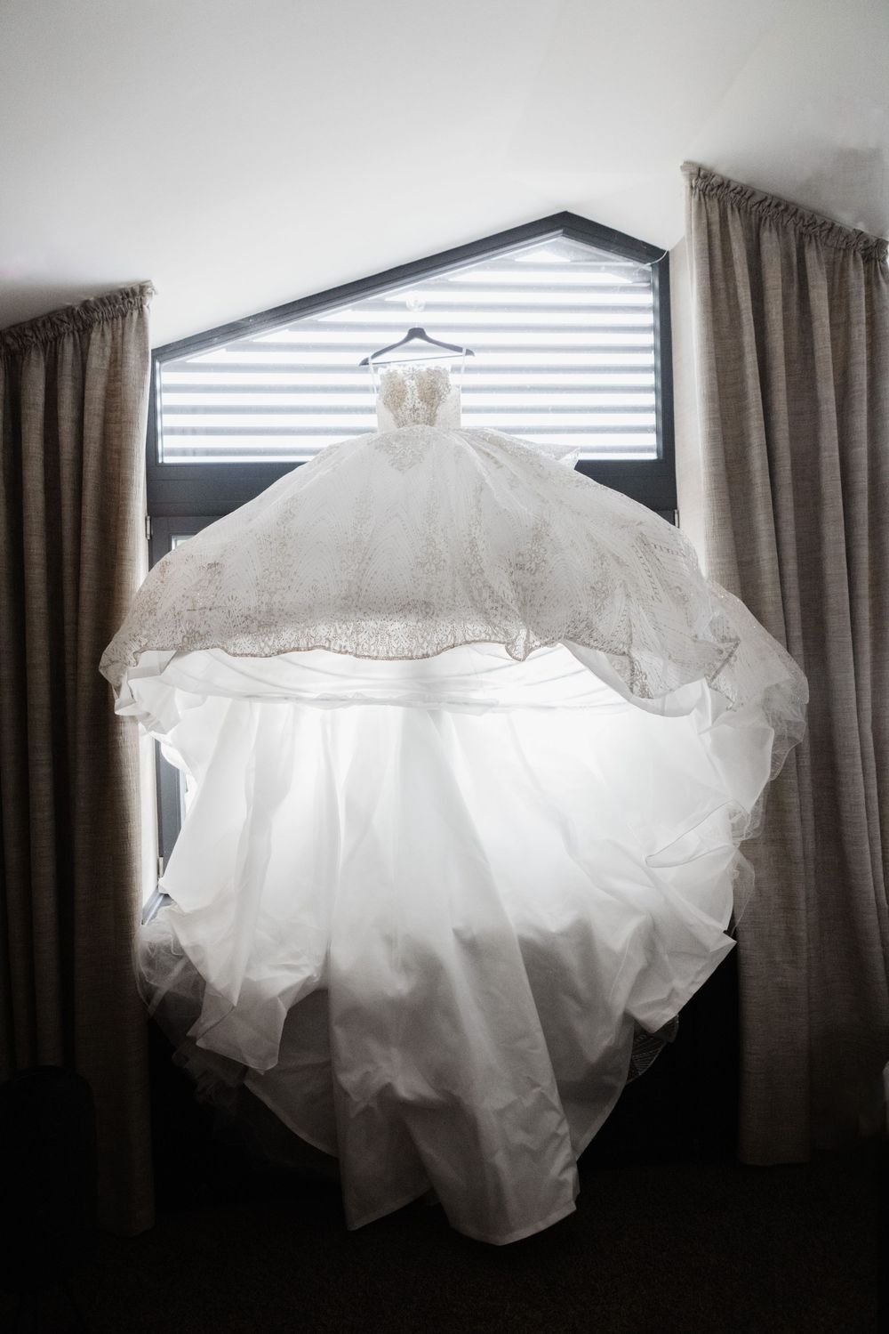Aufwändig besticktes Brautkleid hängt am Fenster – Getting-ready zur freien Trauung im Waldrestaurant Höfer in Sonsbeck.