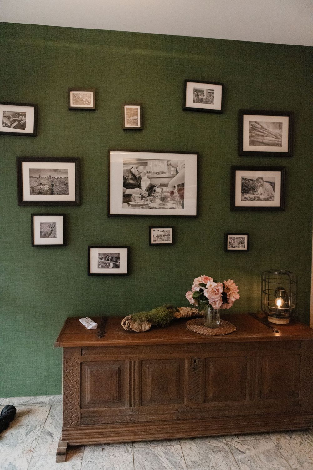 Grüne Wand mit Vintage-Bildern, Holztruhe und Rosen – stimmungsvolle Deko im Waldrestaurant Höfer in Sonsbeck.