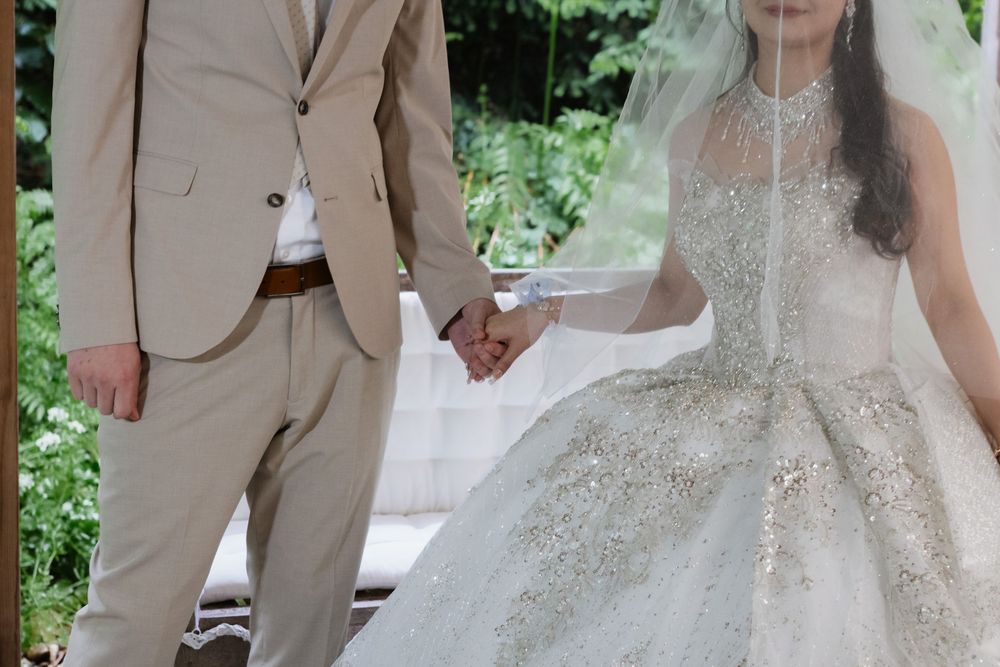 Brautpaar Hand in Hand: heller Anzug trifft funkelndes Brautkleid – deutsch-chinesische freie Trauung in Sonsbeck.