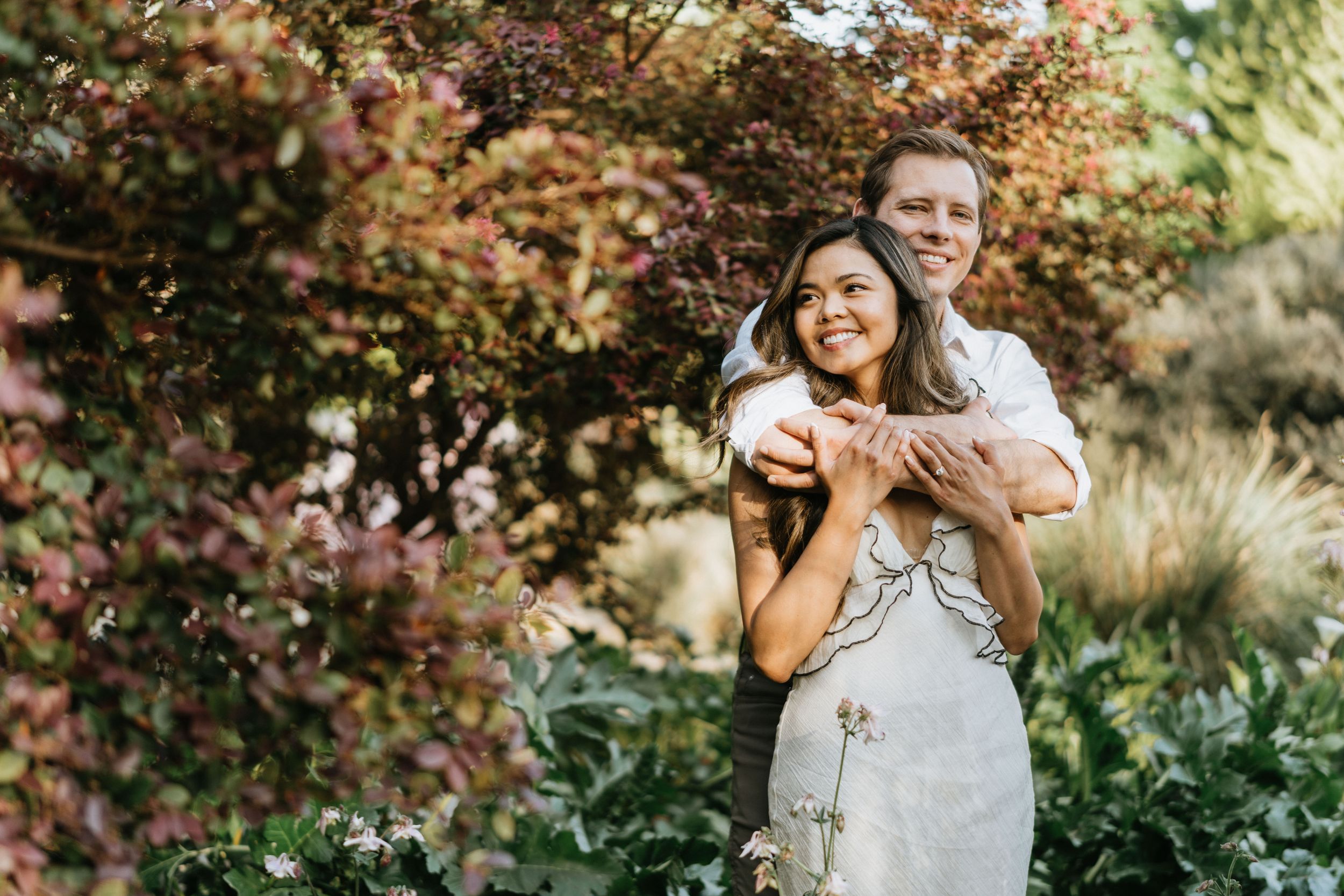 Jeff embracing Mariel from behind during their engagement session in Arcadia