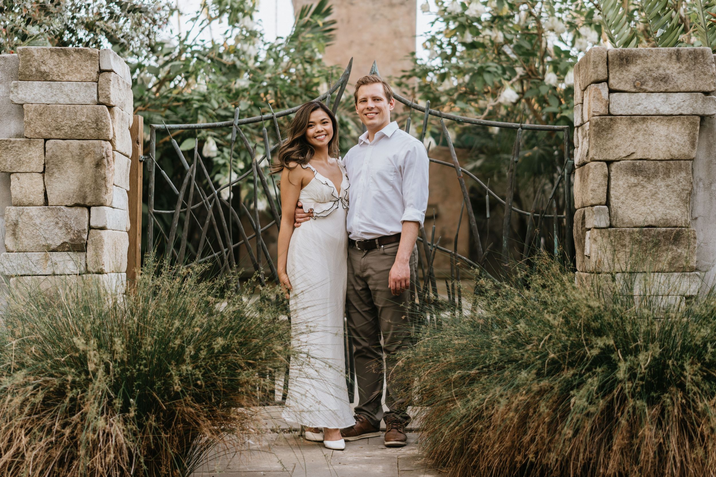 Mariel and Jeff posing beneath the historic stone gate at the Los Angeles County Arboretum.
