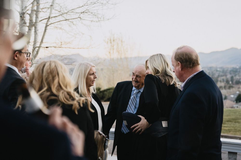 Group of formally dressed adults socializing outdoors at a mountain venue during a daytime event.