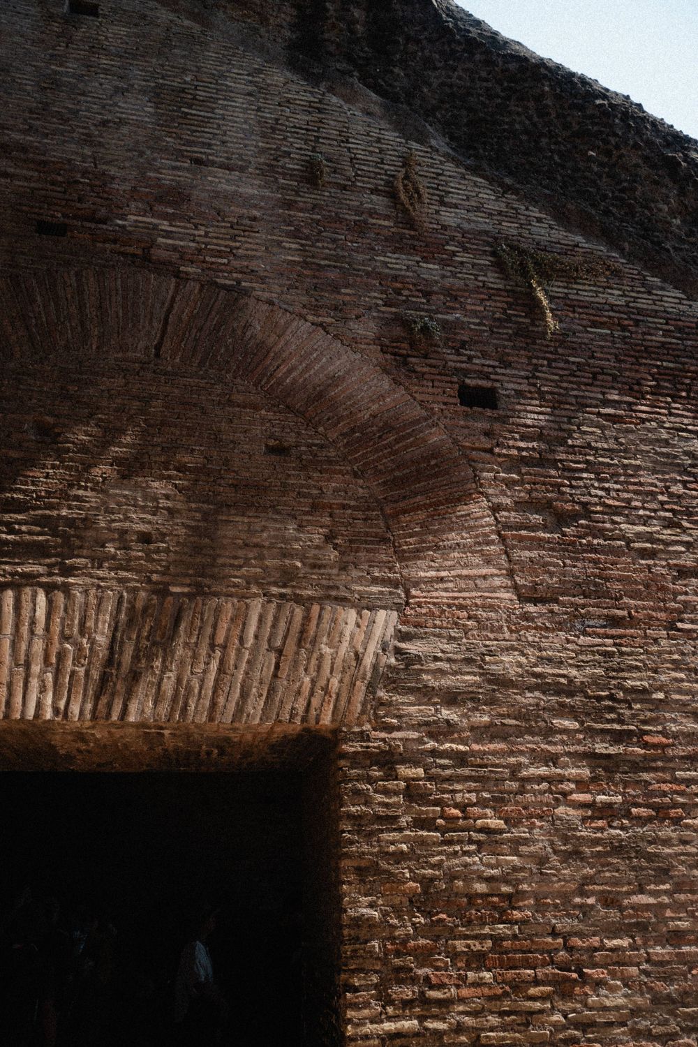 Ancient Roman brick wall with arched doorway showing detailed masonry and weathered terracotta brickwork of historic ruins.