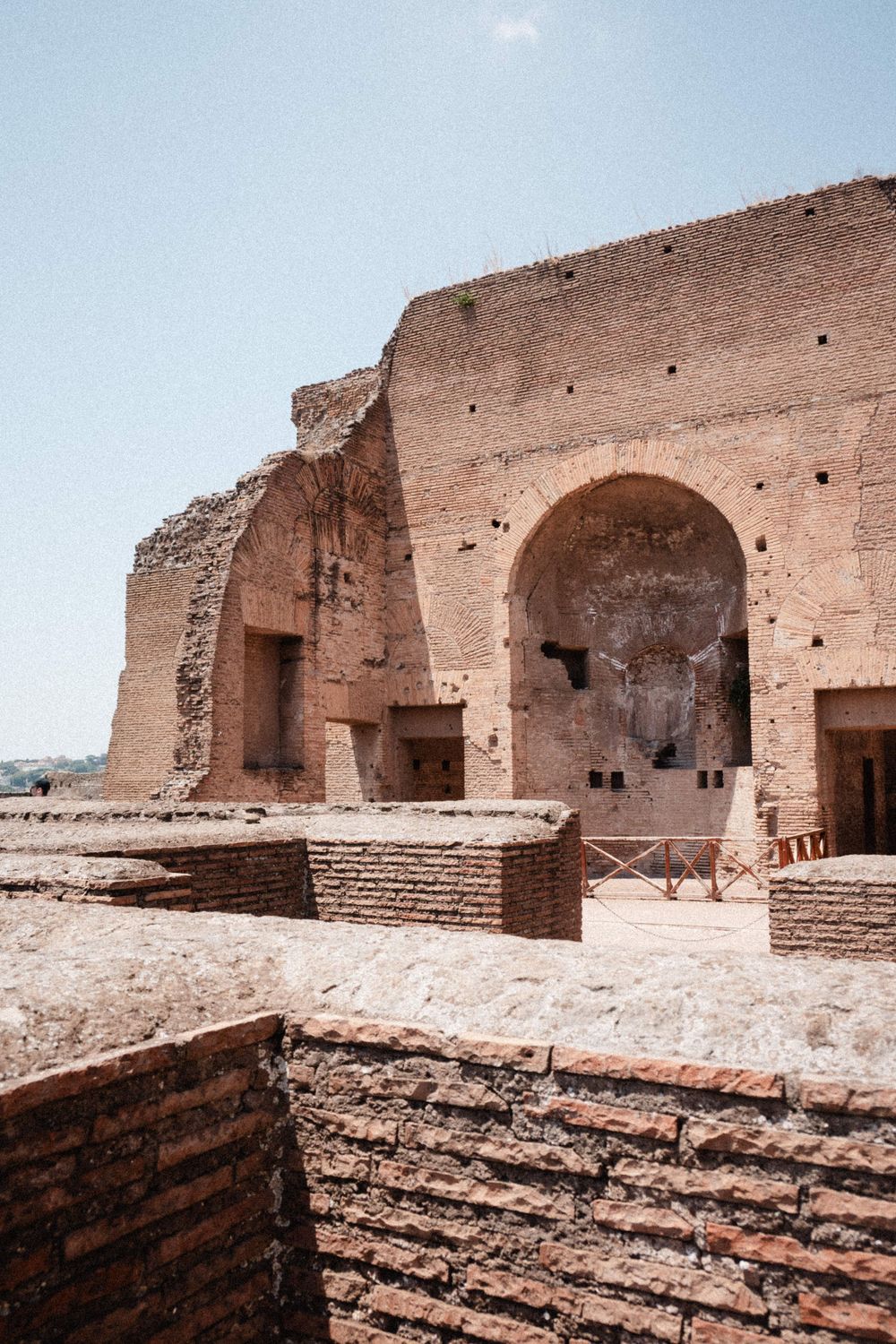 Ancient Roman ruins with large brick arched walls and layered stonework under a clear sky.