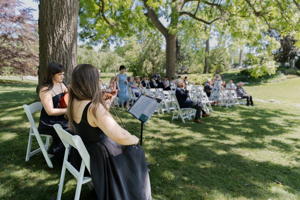 Outdoor ceremony space under the trees with guests and musicians at the civic garden complex in london, ontario.