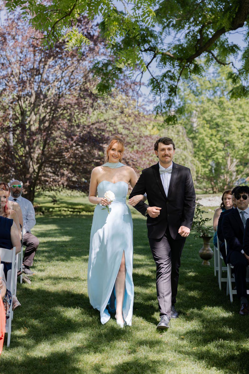 Groomsmen walking with bridesmaid in the aisle at an outdoor wedding ceremony at the civic garden complex in london, ontario.