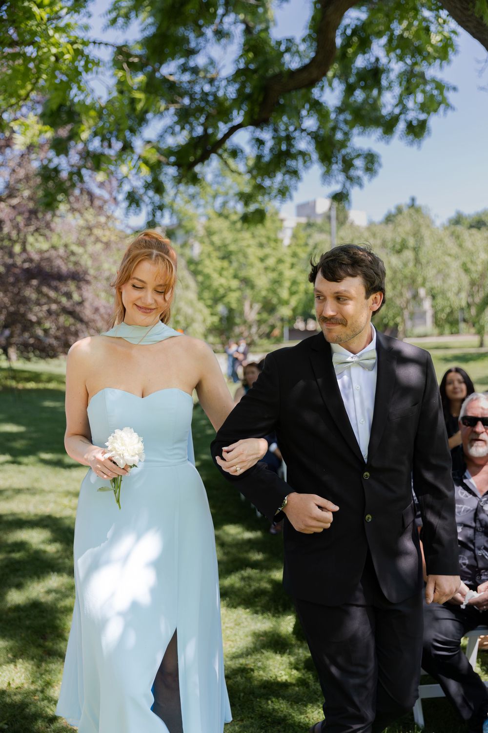 Bridesmaid and groomsmen smiling surrounded by greenery during an outdoor ceremony at the civic garden complex in london, ontario.