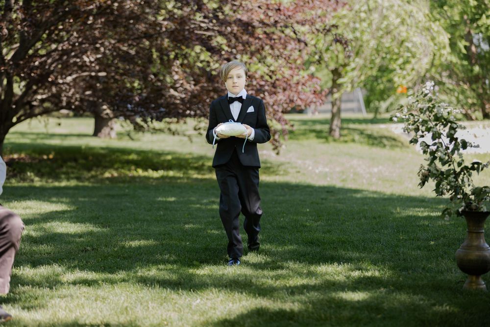Ring bearer surrounded by greenery at an outdoor ceremony at the civic garden complex in london, ontario.