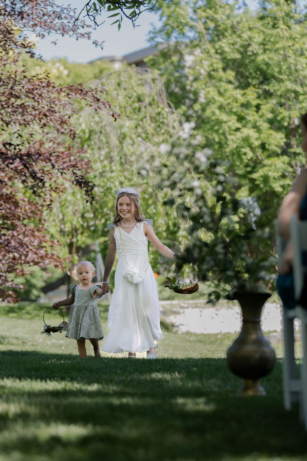Flower girls walking down aisle surrounded by greenery at the civic garden complex in london, ontario.