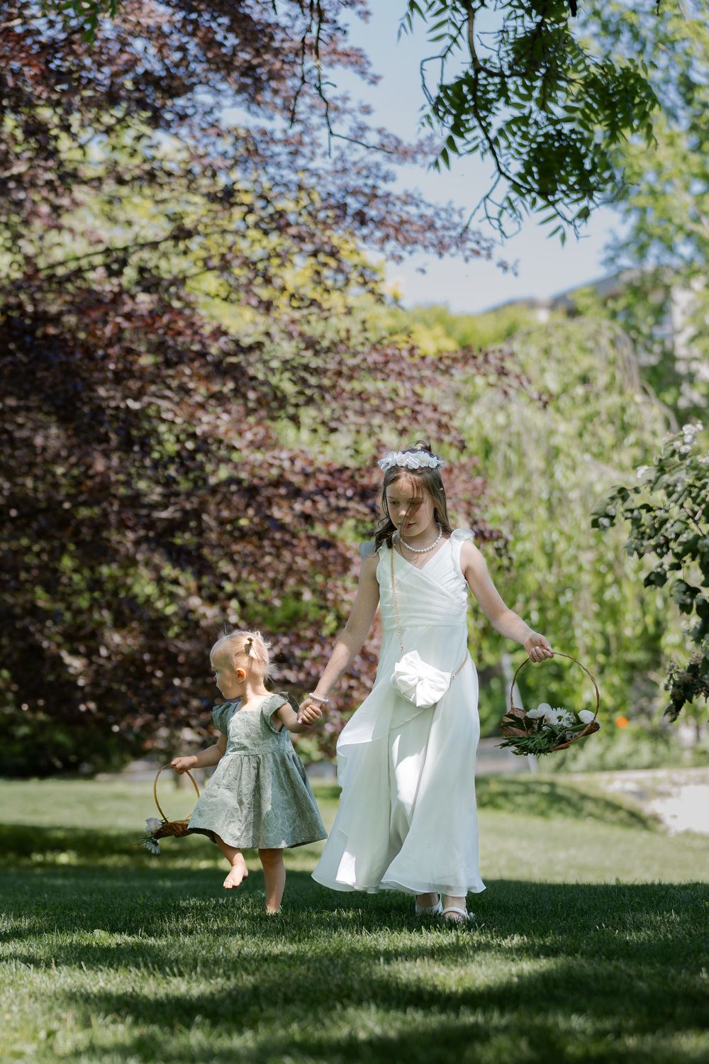 Flower girls walking down an aisle during an outdoor ceremony under the trees at the civic garden complex in london, ontario.