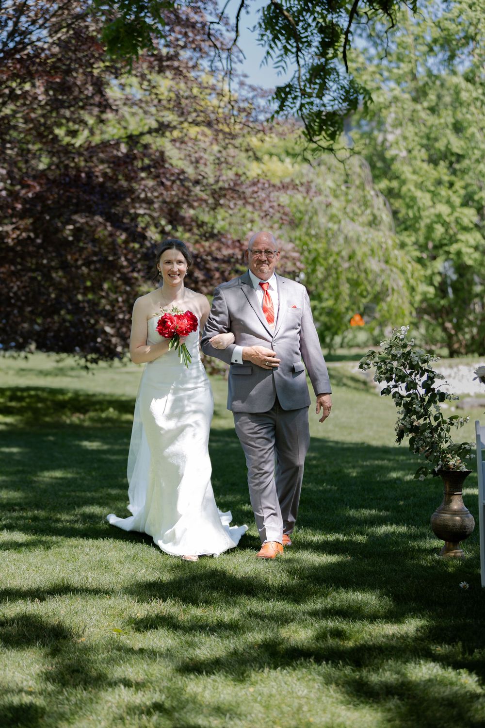 Bride and father walk down the aisle at their outdoor ceremony under the trees at the civic garden complex in london, ontario.
