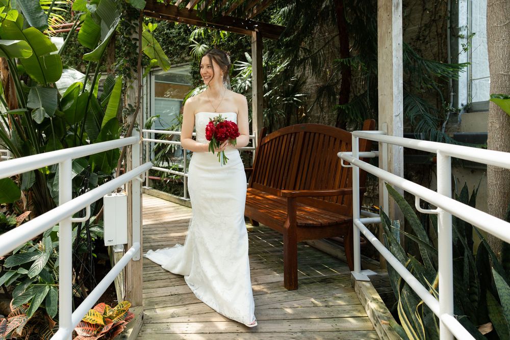 Bride walking down walkway in the conservatory for first look with groom at the civic garden complex in london, ontario.