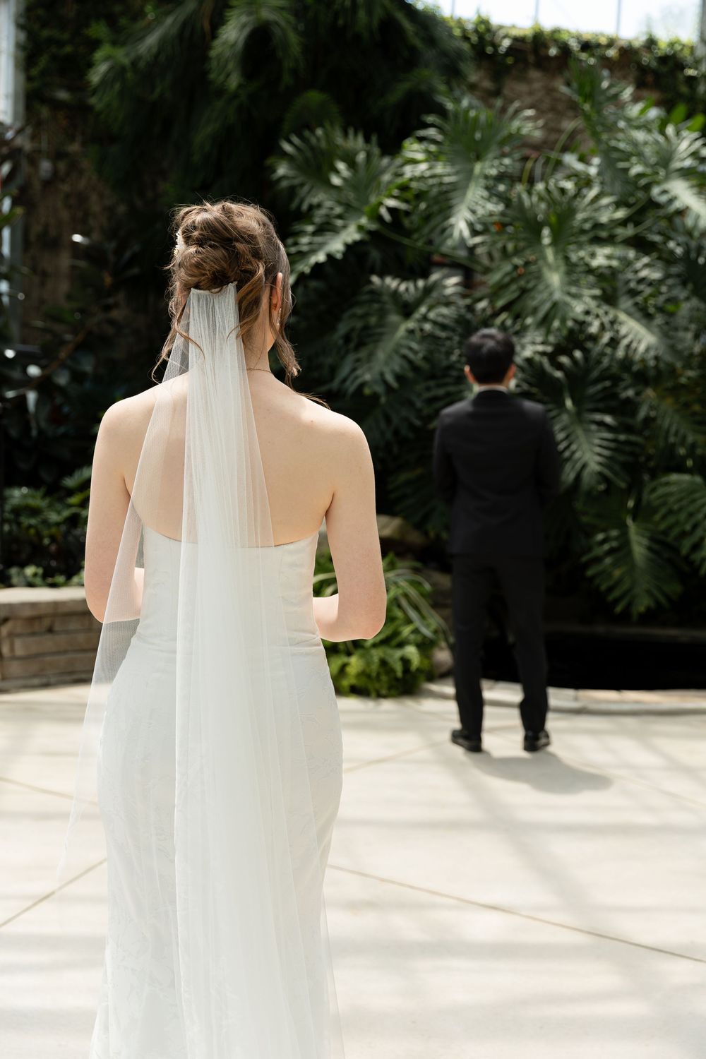 Bride looking at groom during first look in the conservatory at the civic garden complex in london, ontario.