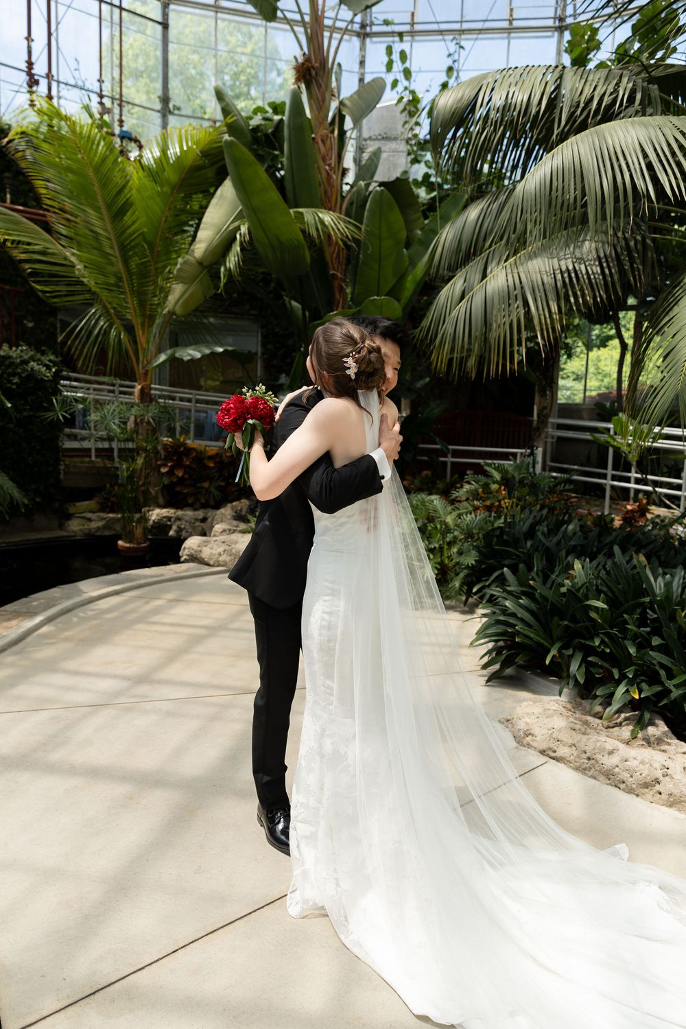 Bride and groom embrace during their first look in the conservatory surrounded by greenery at the civic garden complex in london, ontario.