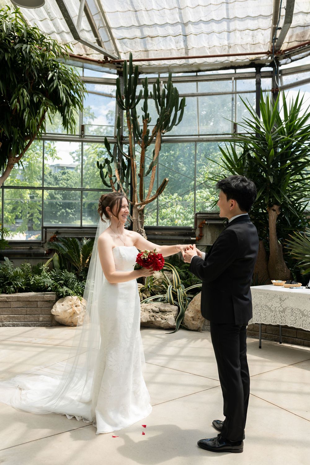 Groom twirls his bride during first look in the conservatory at the civic garden complex in london, ontario.
