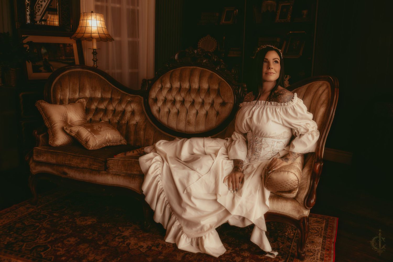 Woman sitting on victorian couch in photo studio located in Saltsburg, pennsylvania. White flowing dress with ethereal vibes.