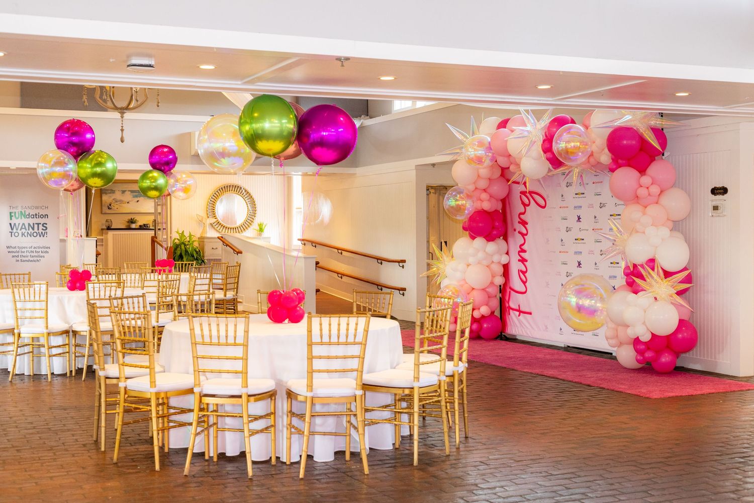 A tented wedding reception venue overlooking the water with guests seated at round tables.