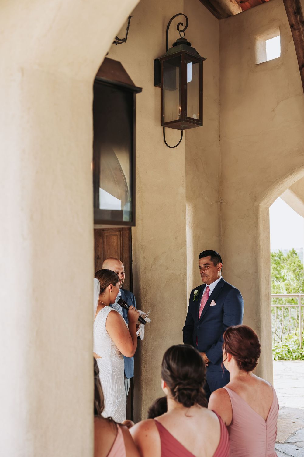 Groom awaiting bride at rustic outdoor wedding ceremony venue entrance.