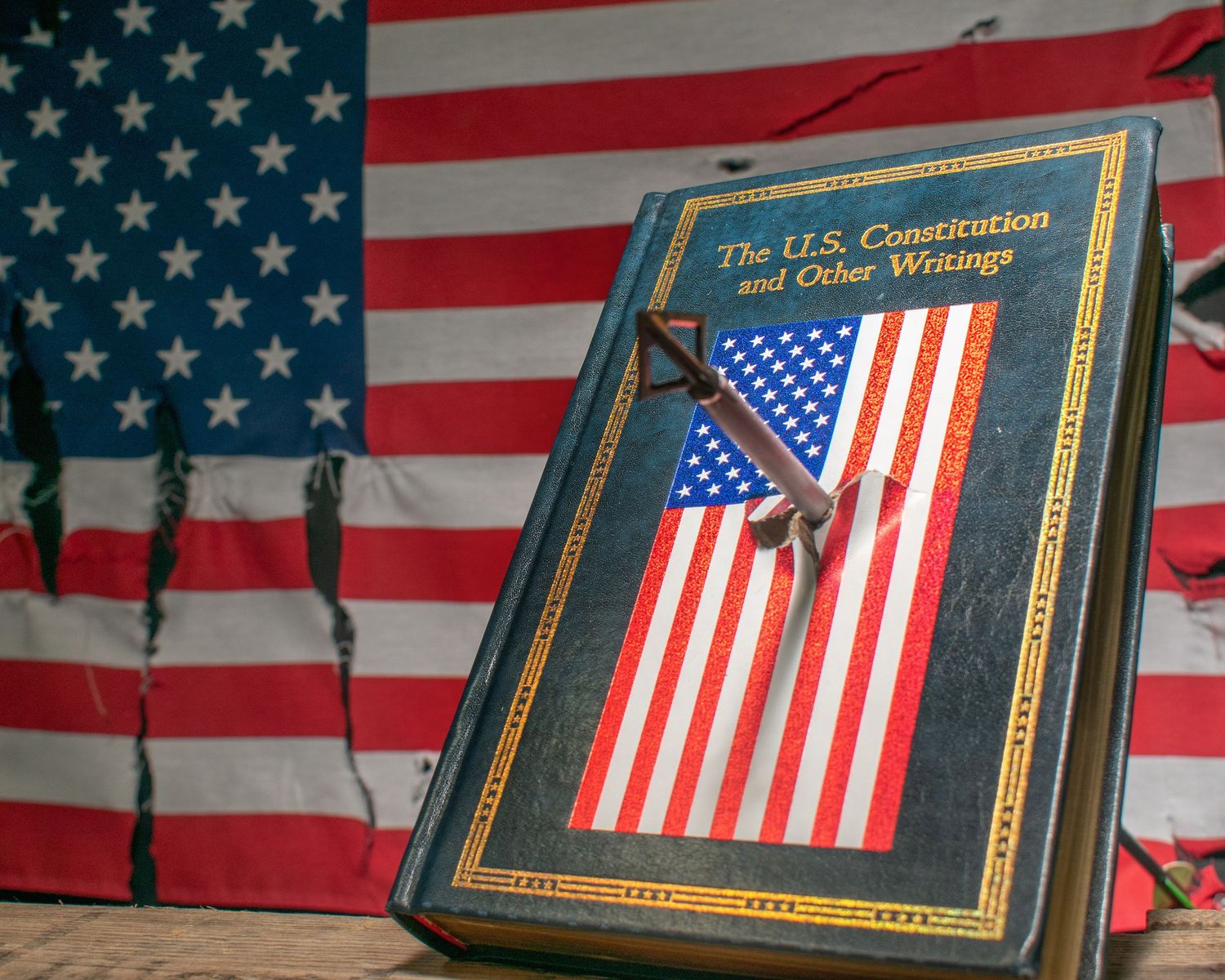 Book titled The U.S. Constitution and Other Writings resting against an American flag backdrop.