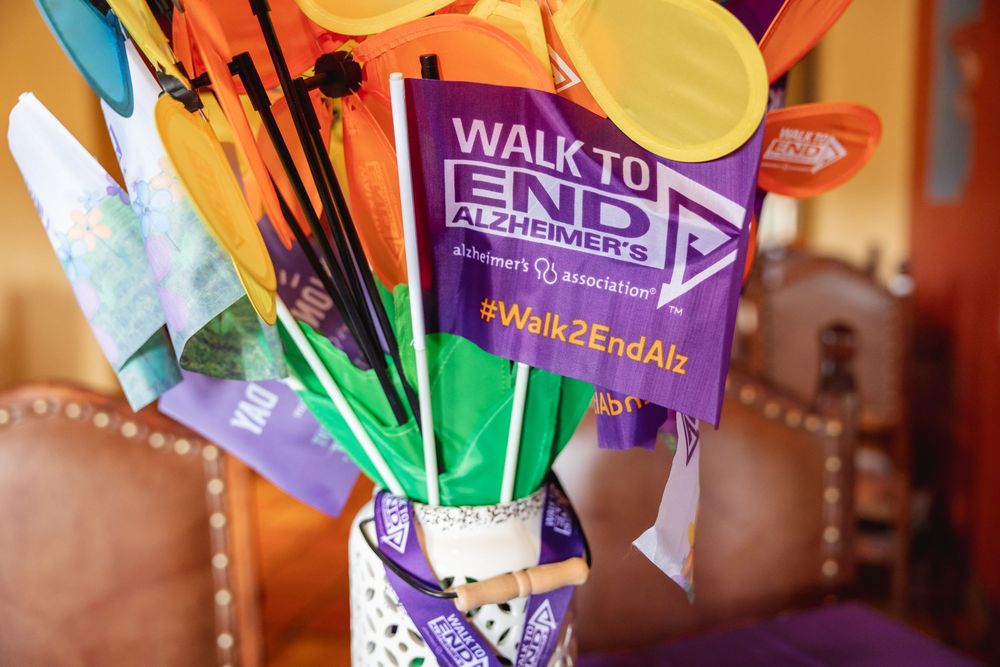 Colorful Walk to End Alzheimer's flags and pinwheels displayed in a vase at a fundraising awareness event.