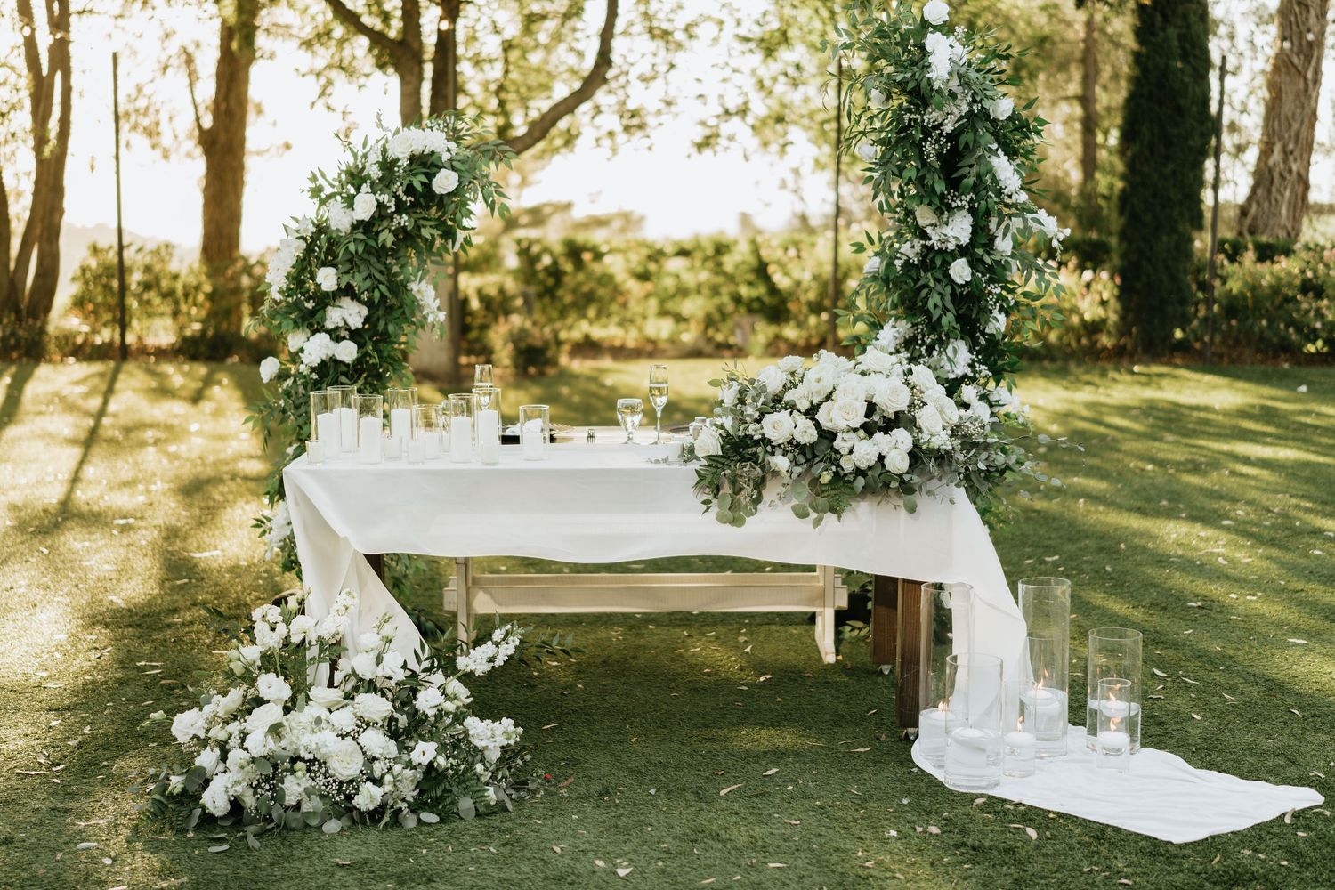Sweetheart table decorated with white flowers and greenery