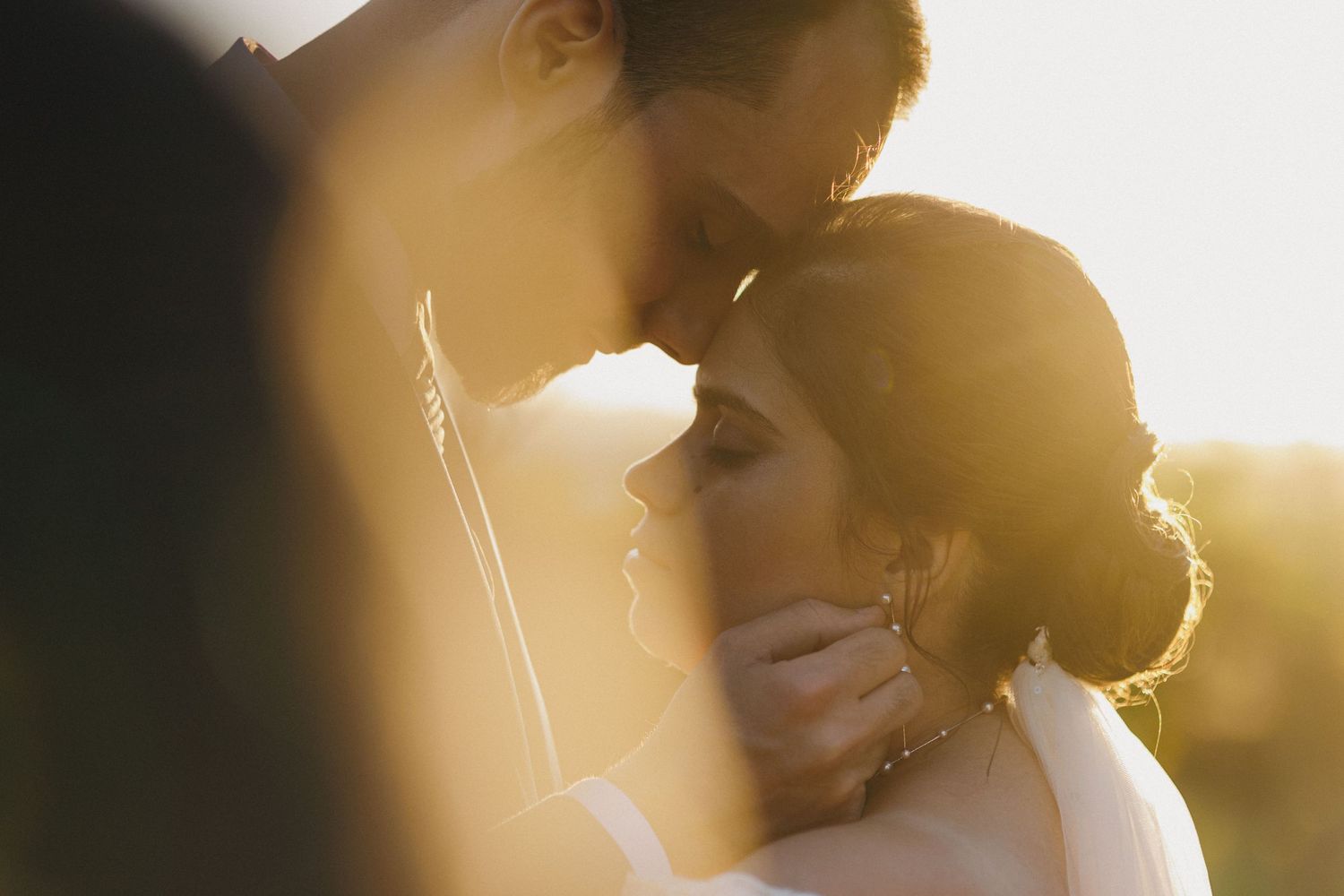 A romantic silhouette of a couple embracing in warm golden sunlight during sunset.