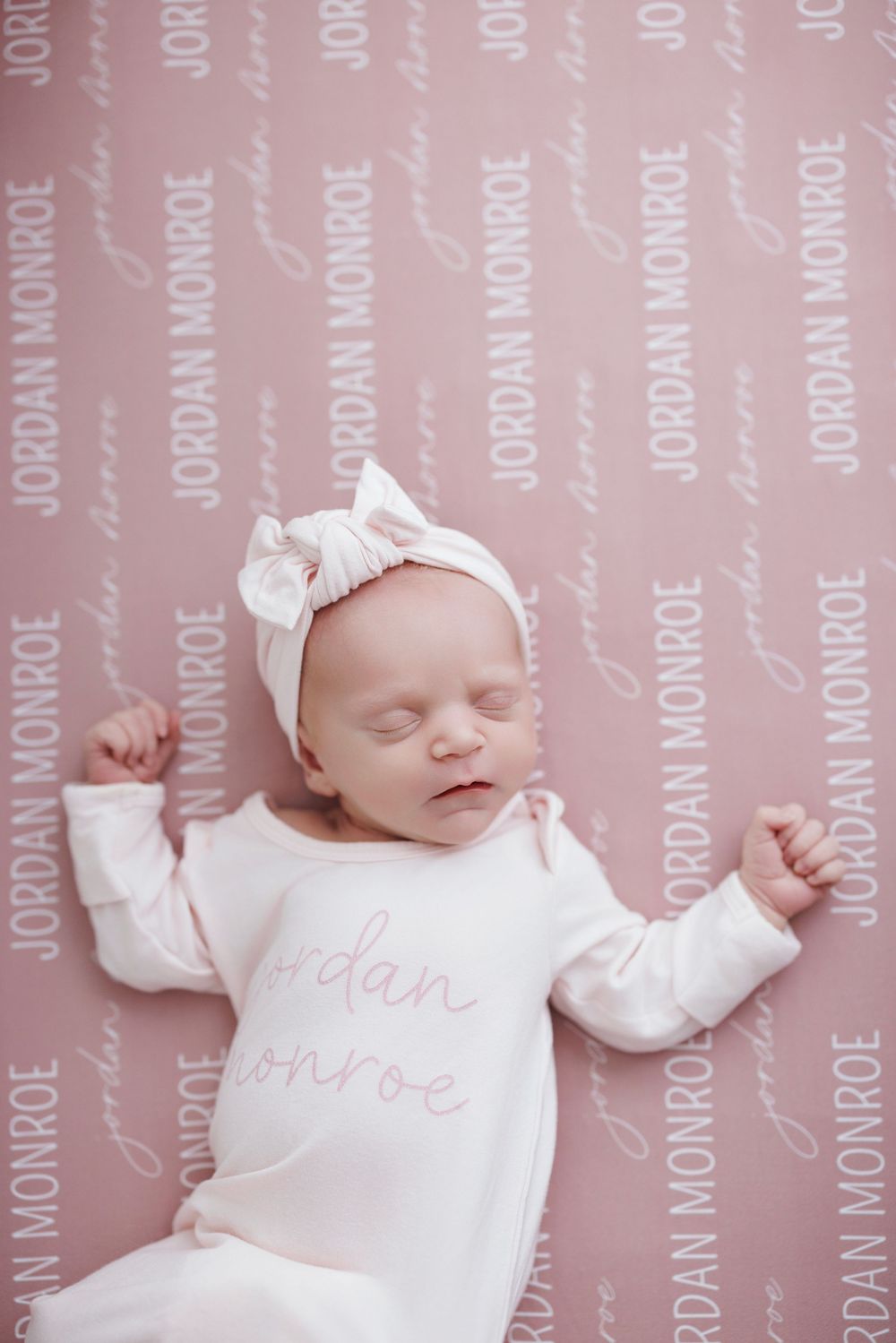 Newborn baby girl named Jordan Monroe sleeps on personalized pink name blanket wearing matching outfit.