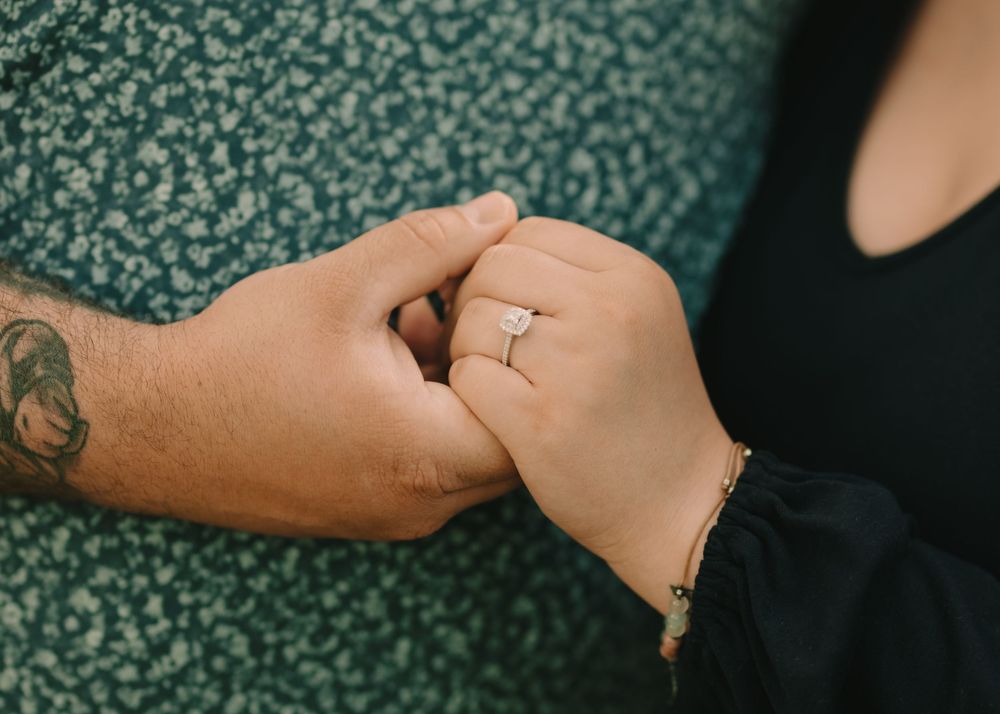 Newly engaged couple holding hands showing off an engagement ring to the camera