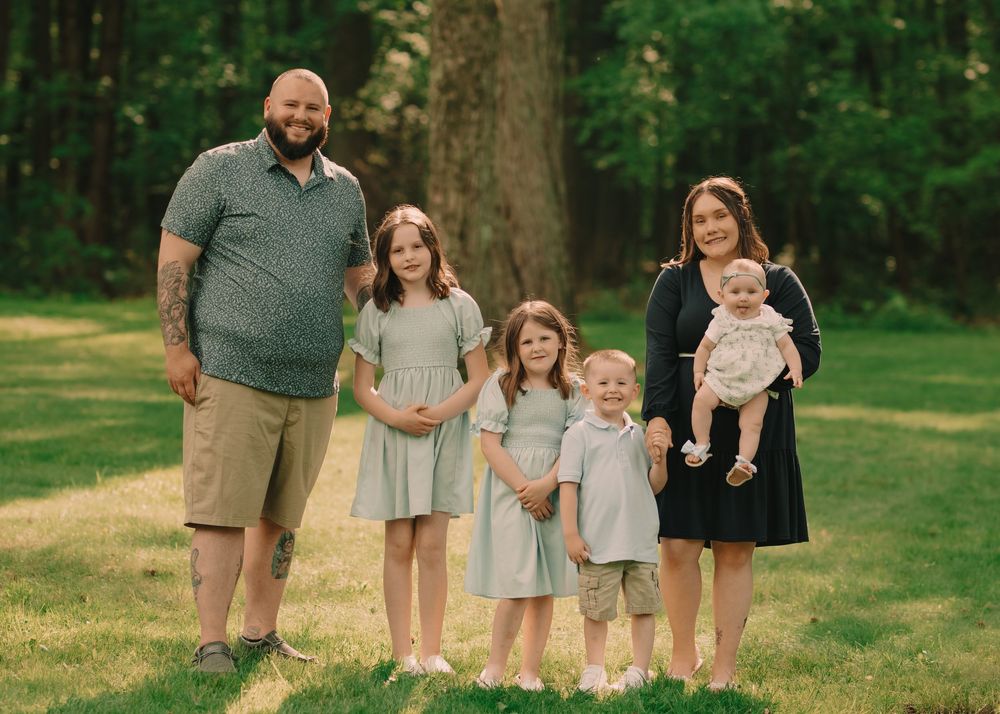 Family of 6 six walking standing in a sun-lit grassy field holding hands