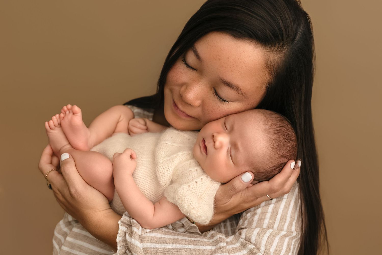 New mom snuggles her newborn girl, who is dressed in a soft, white, angora romper, captured by Charlottesville baby photographer.