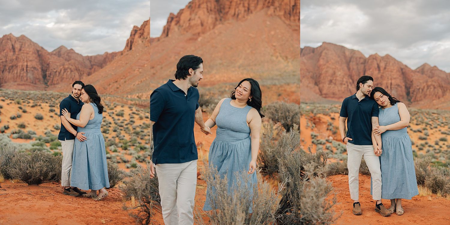 Couple poses in desert landscape with red rock formations, woman in blue dress and man in navy shirt.