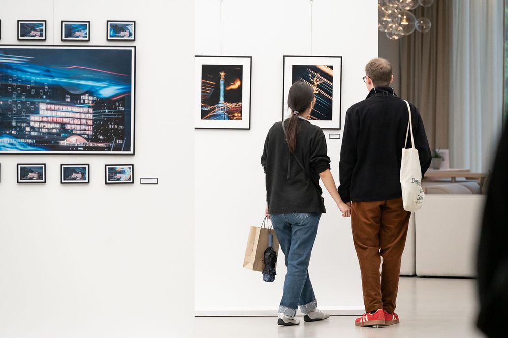 Couple viewing framed photography artwork on white gallery walls during an art exhibition.