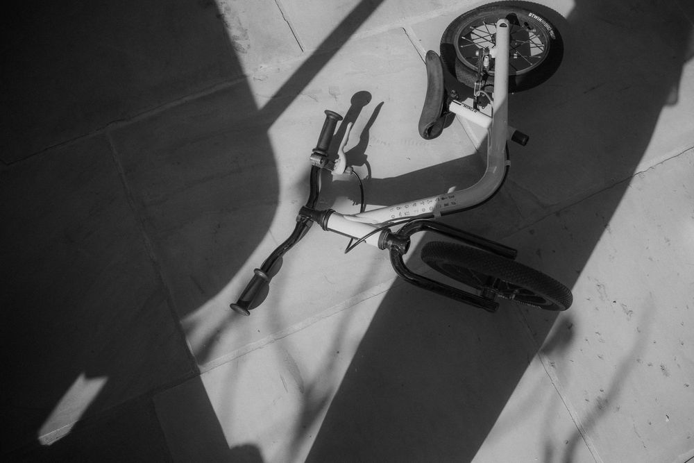Zwart-witfoto van een omgevallen loopfietsje | Communiefeest