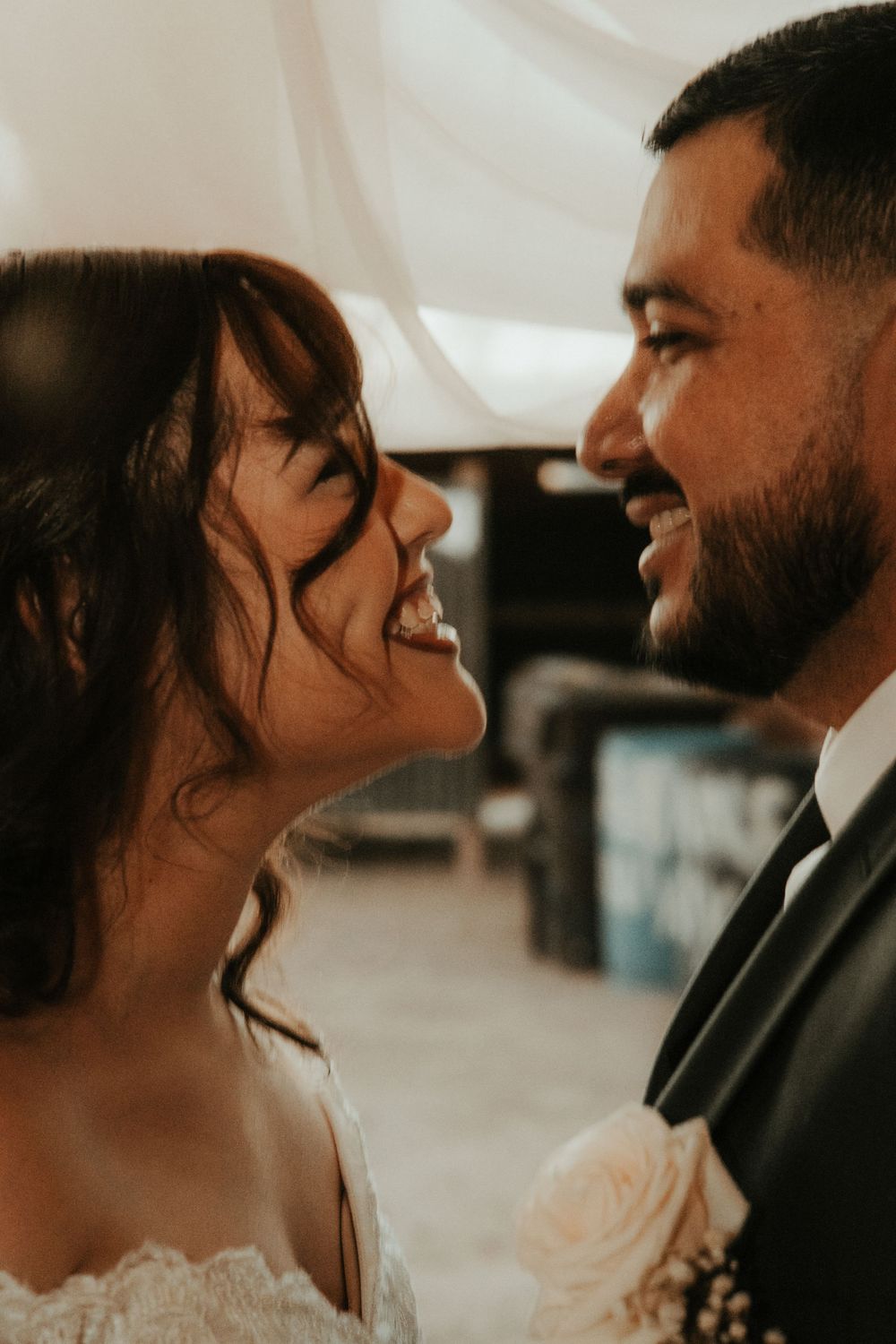 Bride and groom share a joyful moment, smiling at each other on their wedding day.