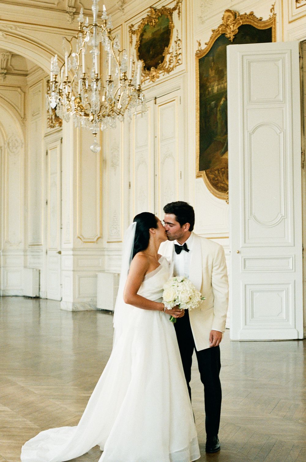 Bride and groom share a kiss in an elegant Parisian ballroom. Versailles wedding photographer, Paris film wedding photographer, film 35mm