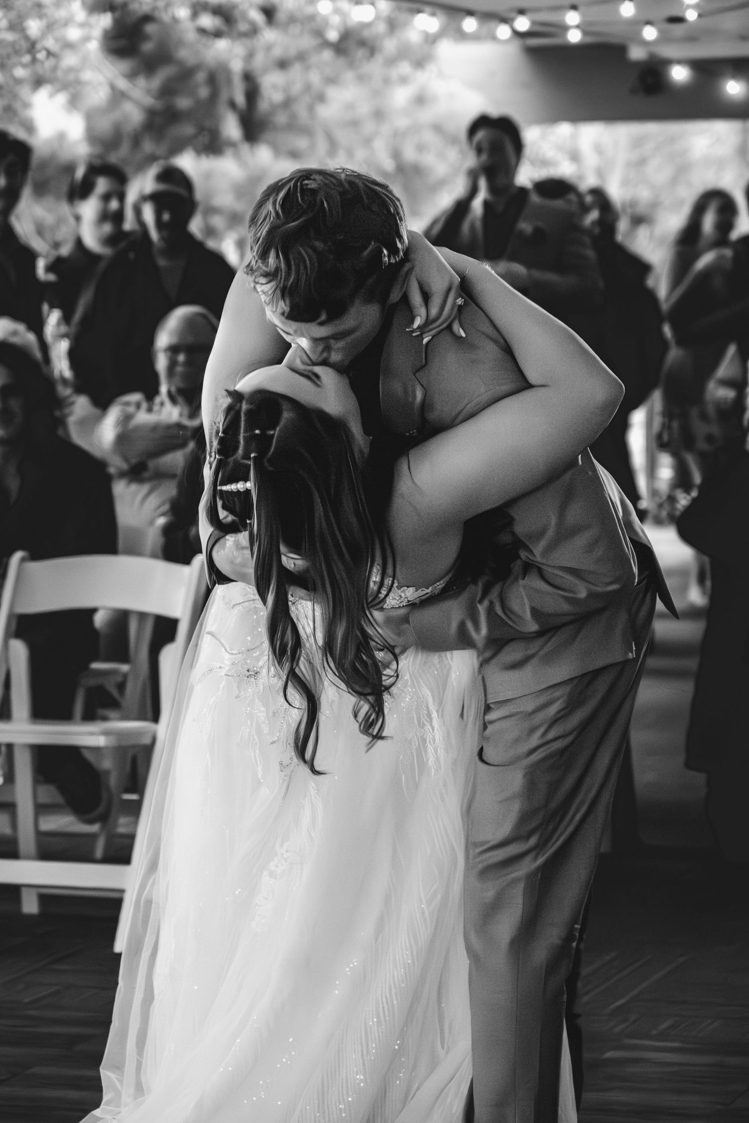 Black and white photo of a couple sharing a romantic first dance embrace at their wedding reception.