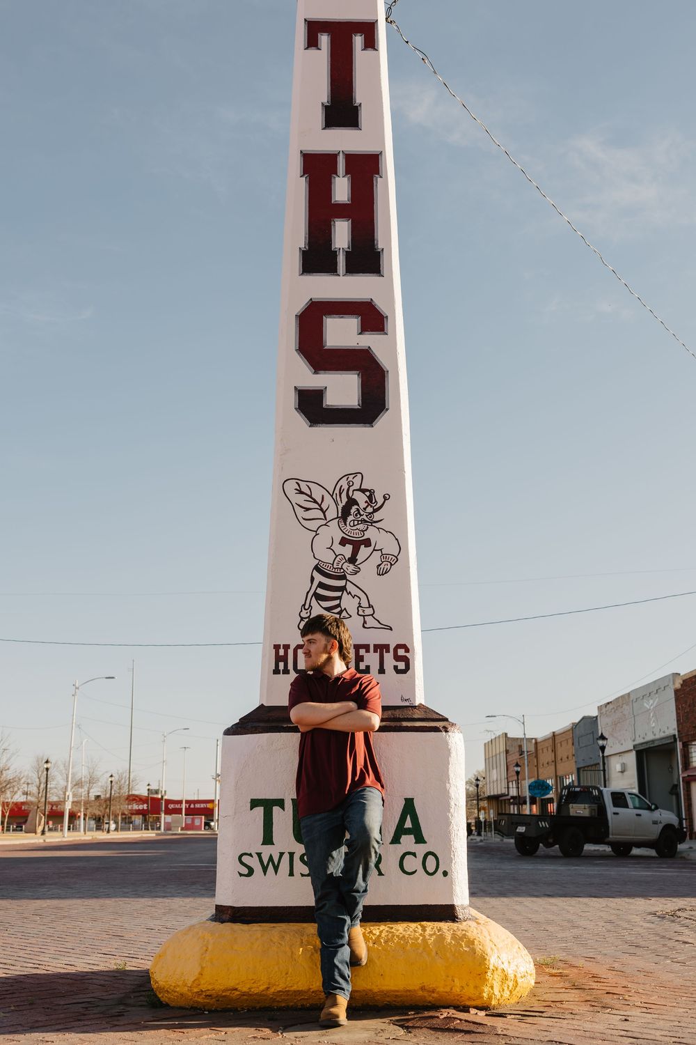A guy wearing red shirt poses next to popular monument in downtown Tulia, Texas during his senior portraits.