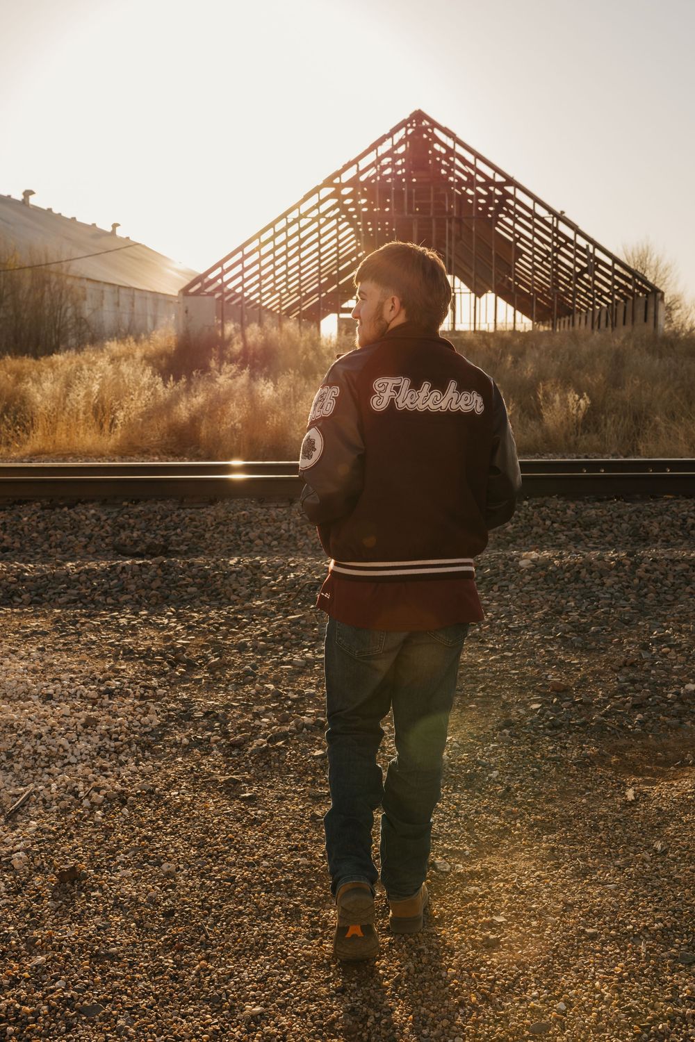 A guy wearing letterman jacket explores downtown Tulia, Texas for his senior portraits.