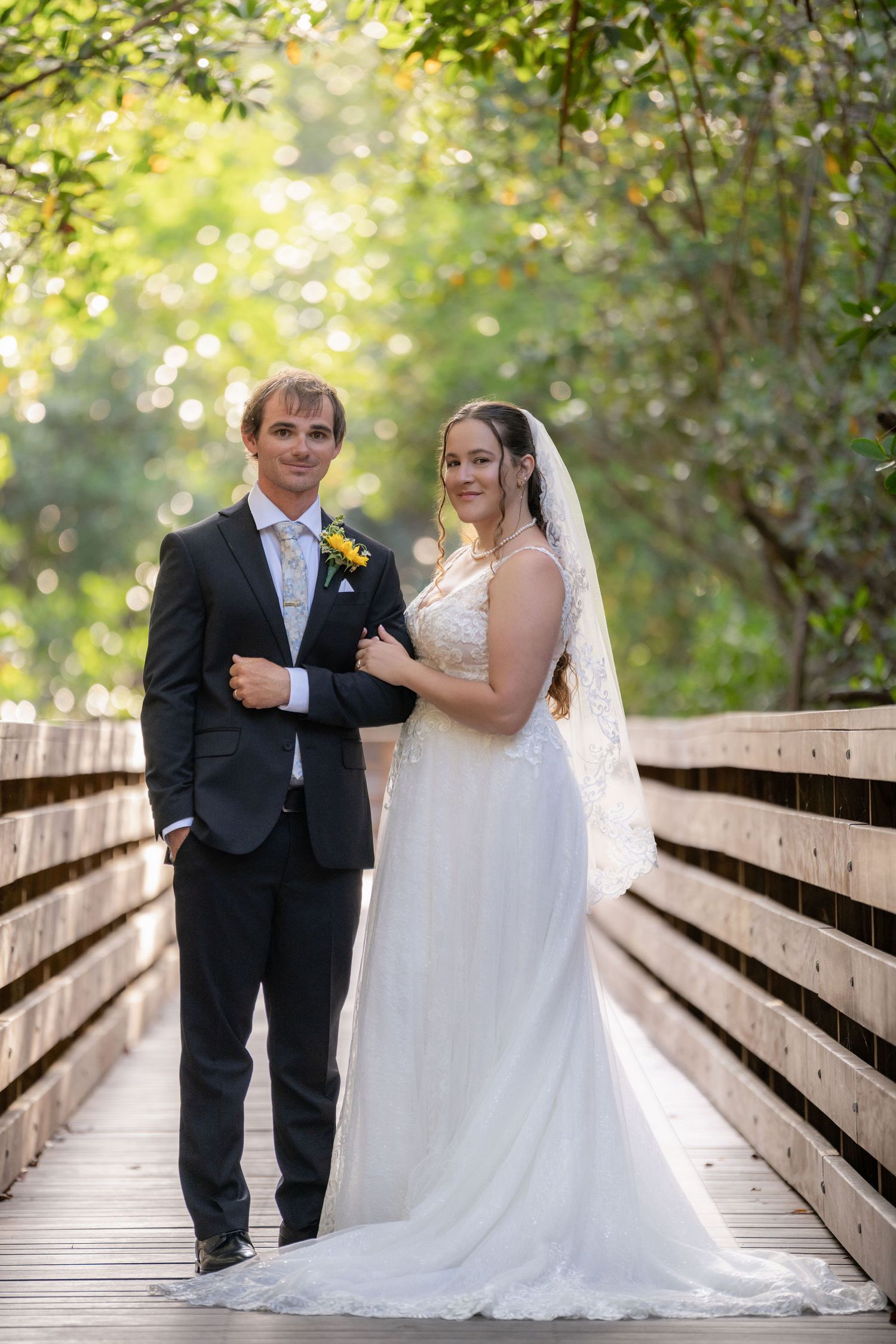 Bride and groom on the mangrove boardwalk with dappled light behind them at Indian Riverside Park