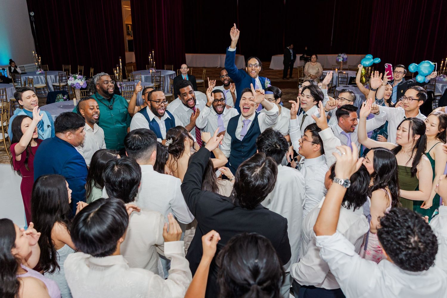 Diverse group of guests celebrating and dancing together at a lively wedding reception party.