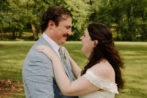 Bride and groom smile warmly at each other in a close embrace during outdoor wedding portraits.