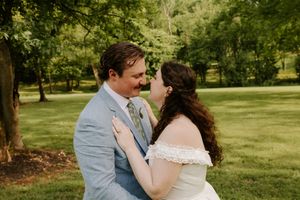 Bride and groom smiling and gazing at each other closely in a lush green outdoor wedding portrait.