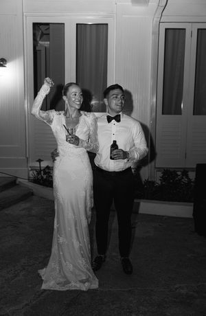 Bride and groom celebrate joyfully outdoors at night in black and white wedding photo.