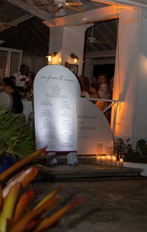 Elegant wedding seating chart display for Stephanie and Jonathan, illuminated by warm candlelight at an outdoor venue.