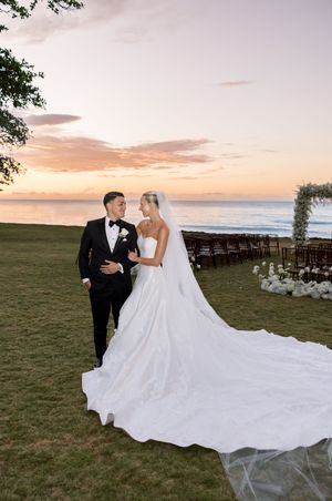 Bride and groom share a romantic moment at sunset beach wedding ceremony with ocean views and floral arch.