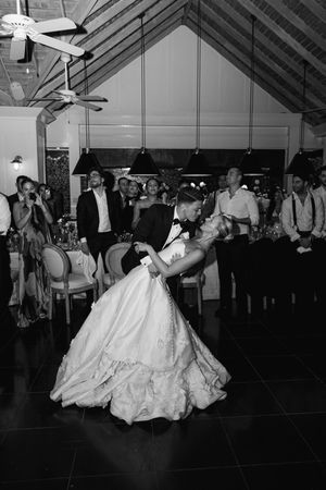 Black and white photo of bride and groom sharing first dance dip at elegant wedding reception.