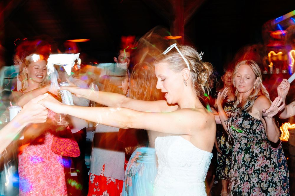 Bride dancing joyfully with guests at a lively wedding reception party.