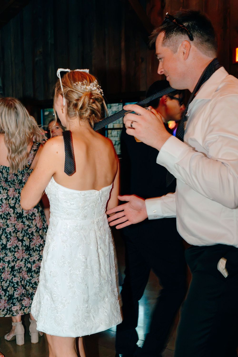 Bride in white lace dress dancing with groom in white shirt at wedding reception.