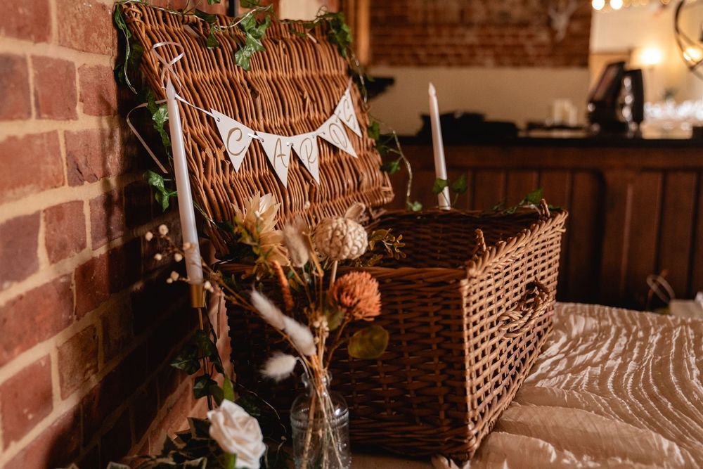 Rustic wedding decor with wicker baskets, candles, bunting, and dried floral arrangements.
